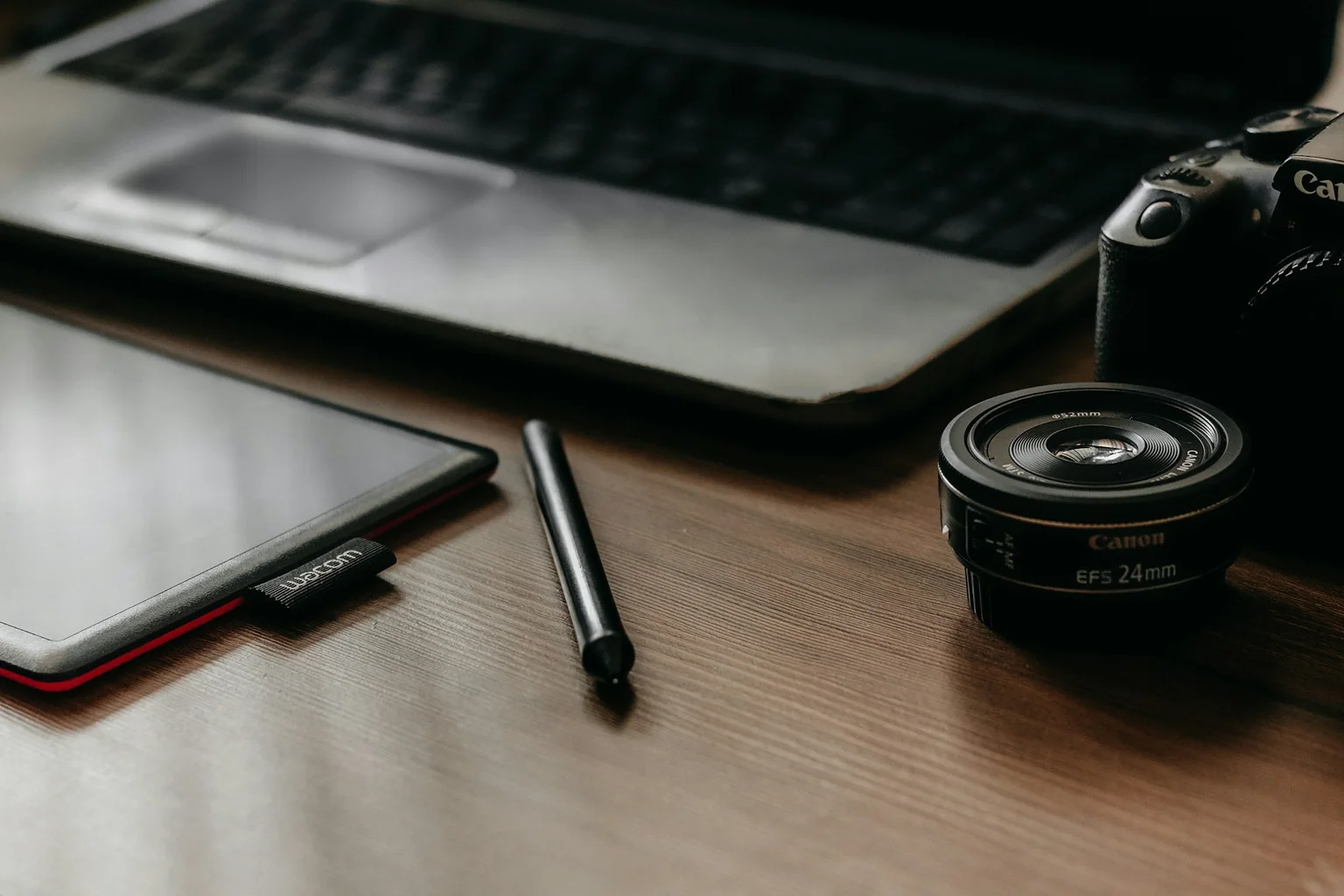 Camera, laptop, and pen arranged on a photographer desk