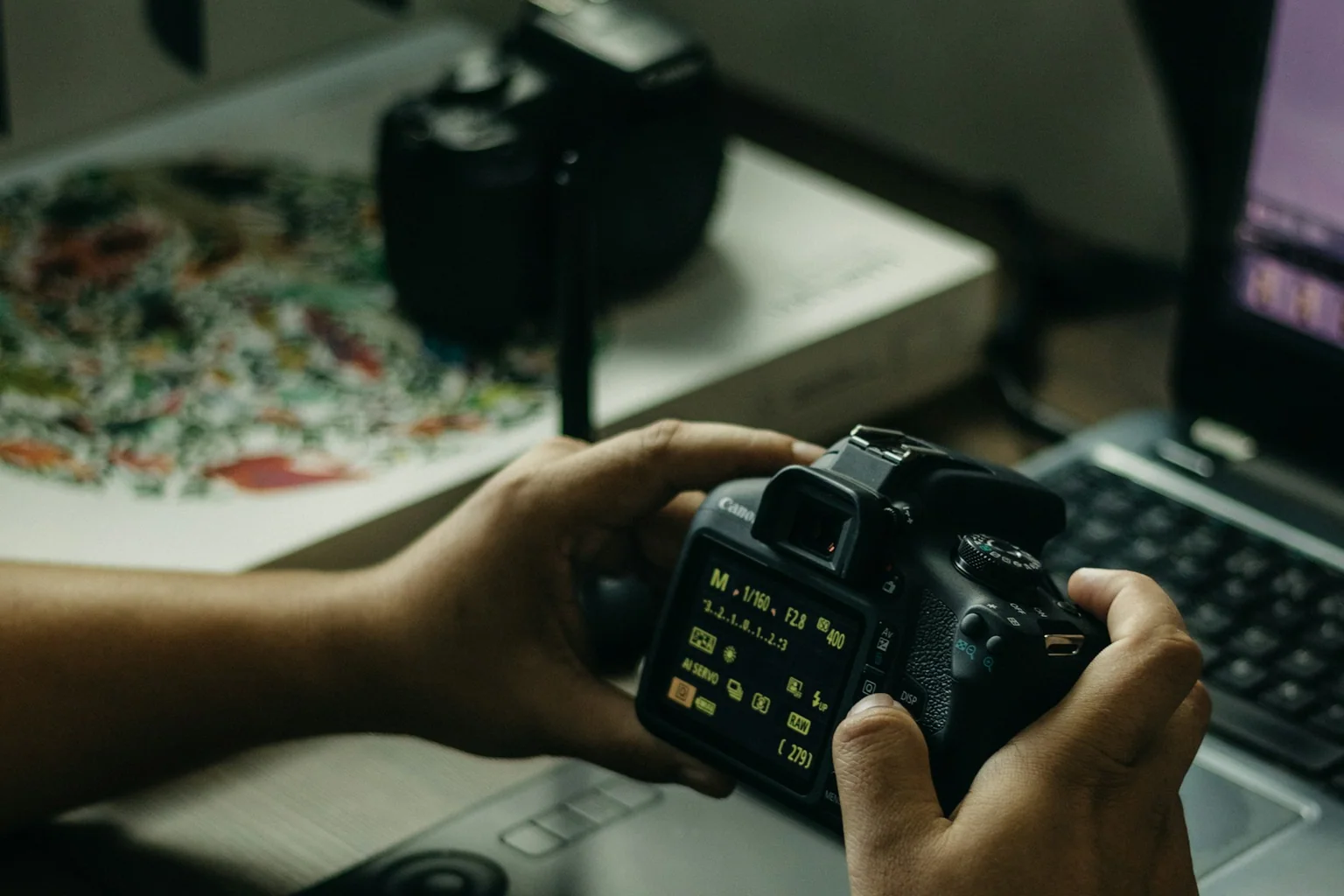 Photographer reviewing camera files beside a laptop